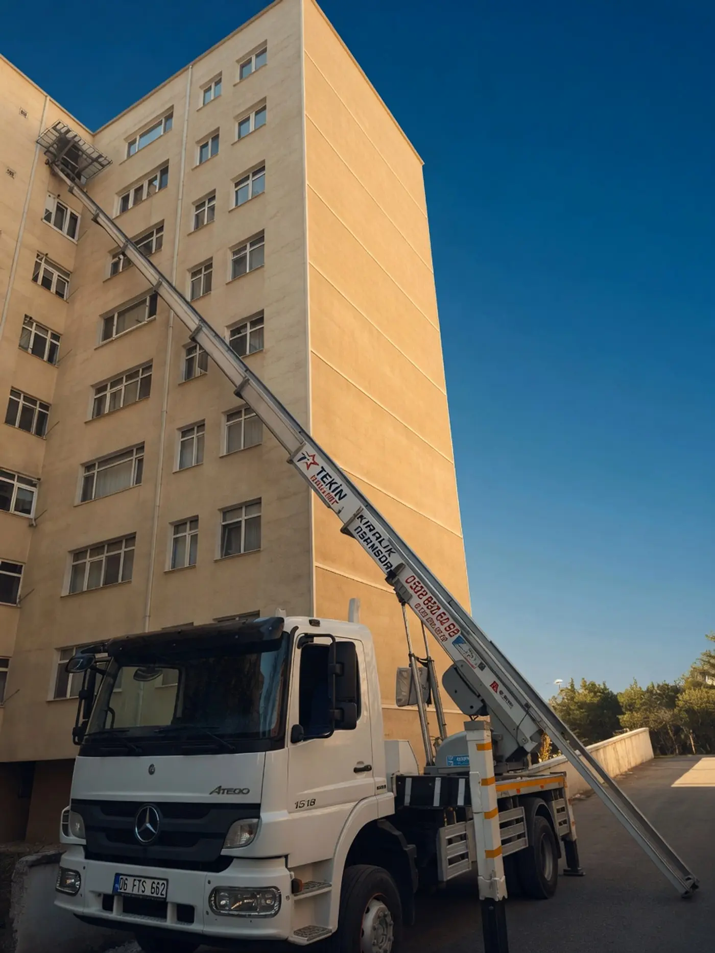 Dış cephe taşıma asansörü apartmanın üst katına uzatılmış, altında Tekin Nakliyat kamyonu